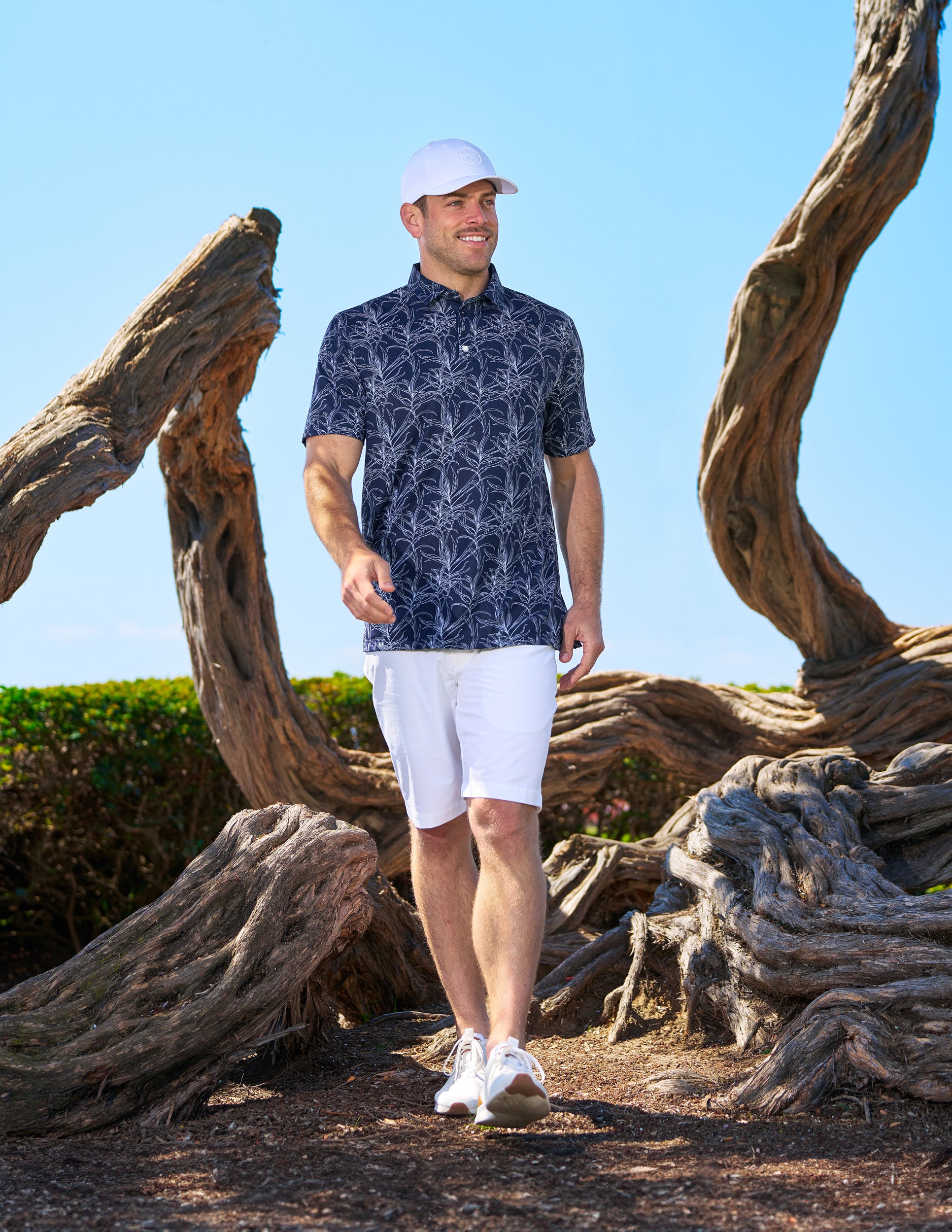 Man standing next to petrified wood wearing Black Clover Live Lucky hat in white.