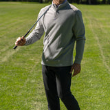 Man wearing grey Black Clover Live Lucky apparel at the golf course holding a club over his shoulder. 