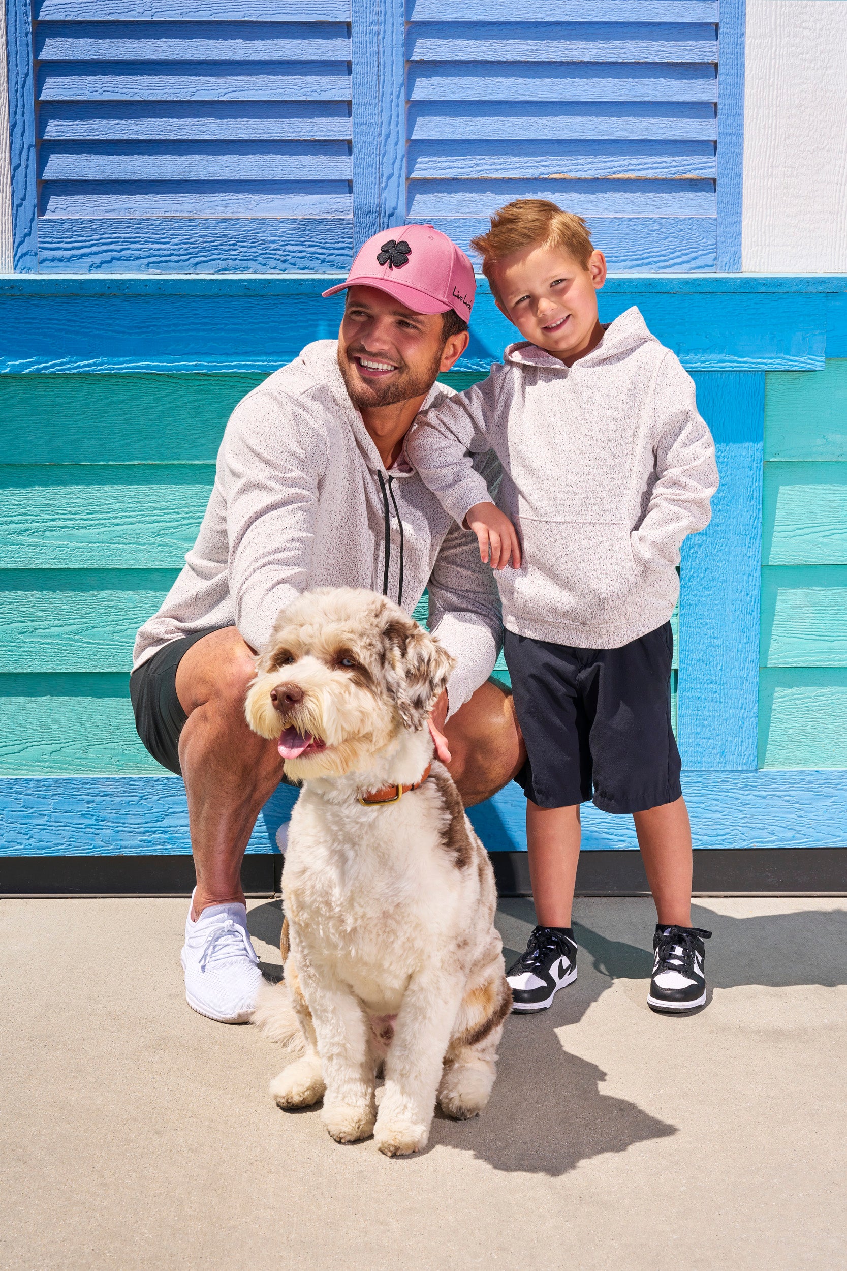 Man wearing Black Clover Live Lucky premium clover hat standing next to his kid and dog.