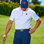 Man standing at golf course in blue Black Clover Live Lucky hat.