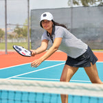 Woman playing pickleball wearing Black Clover Live Lucky premium clover hat in white.